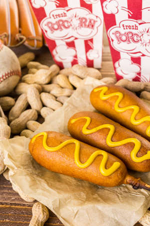 Game day traditional snacks included corndogs and salted peanuts on a wood board.の写真素材