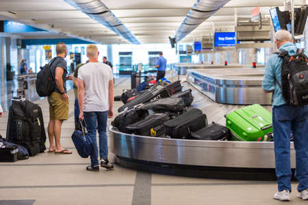 Denver, Colorado, USA-June 22, 2016.  Travelers waiting for their luggage at the baggage carousel.のeditorial素材