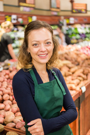 Portrait of a grociery store clerk in front of a vegetable section of the store.の写真素材