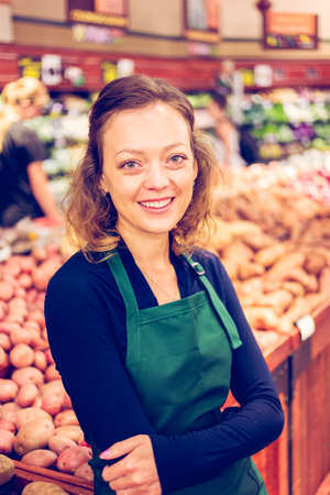 Portrait of a grociery store clerk in front of a vegetable section of the store.の写真素材