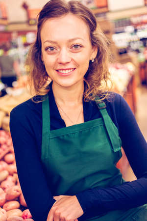 Portrait of a grociery store clerk in front of a vegetable section of the store.の写真素材