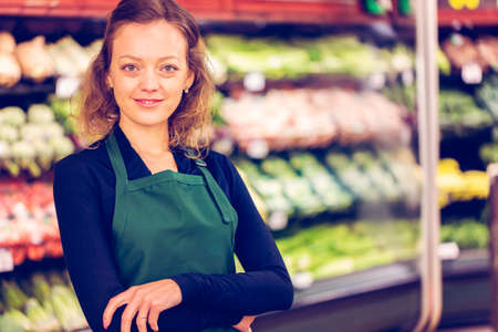 Portrait of a grociery store clerk in front of a vegetable section of the store.の写真素材