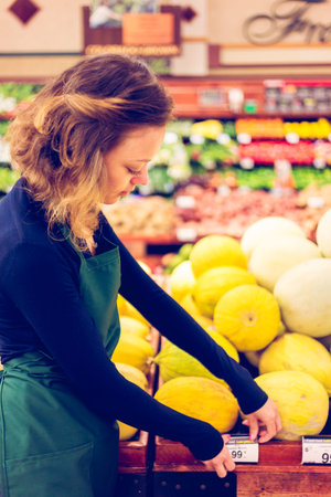 Portrait of a grociery store clerk in front of a vegetable section of the store.の写真素材