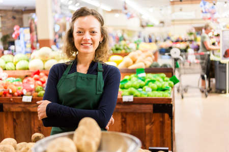 Portrait of a grociery store clerk in front of a vegetable section of the store.の写真素材