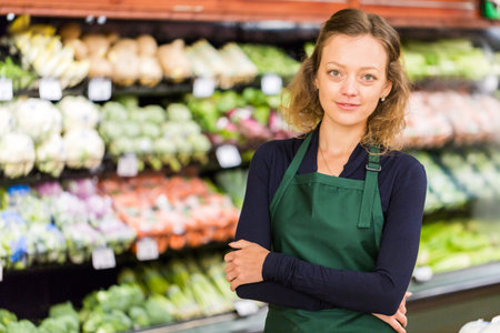Portrait of a grociery store clerk in front of a vegetable section of the store.の写真素材