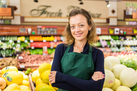 Portrait of a grociery store clerk in front of a vegetable section of the store.の写真素材