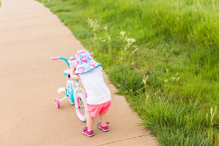 Toddler learning how to ride bicycle on the trail.の写真素材