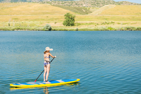 Young woman learning how to paddleboard on small pond.