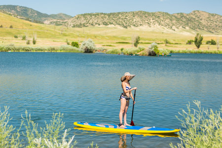 Young woman learning how to paddleboard on small pond.の写真素材