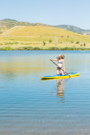 Young woman learning how to paddleboard on small pond.の写真素材