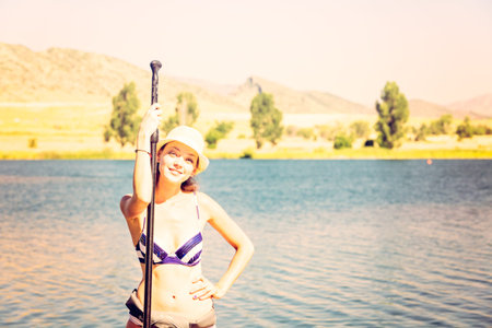 Young woman learning how to paddleboard on small pond.