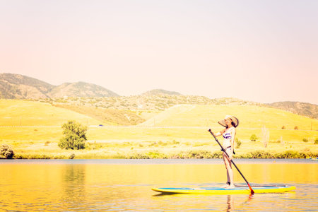 Young woman learning how to paddleboard on small pond.の写真素材