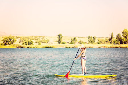 Young woman learning how to paddleboard on small pond.の写真素材