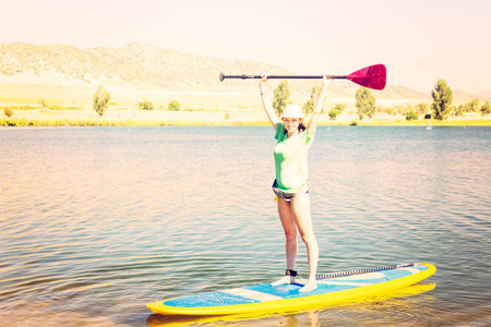 Young woman learning how to paddleboard on small pond.