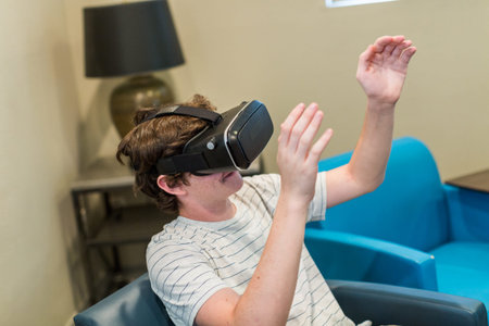 Teenage boy watching movie on VR goggles.