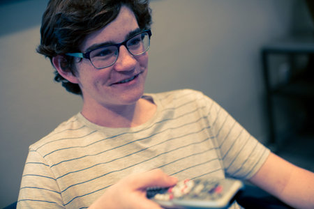 Teenager watching television in media room.