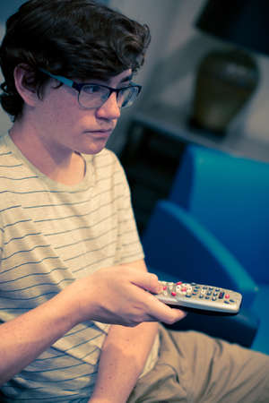 Teenager watching television in media room.の写真素材