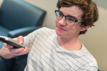 Teenager watching television in media room.の写真素材