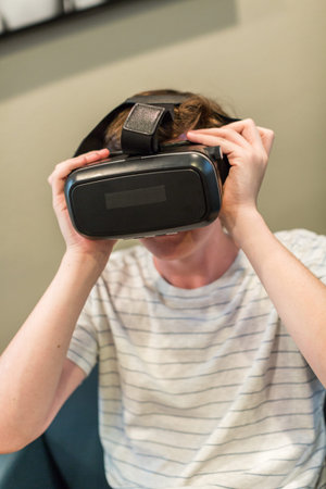 Teenage boy watching movie on VR goggles.