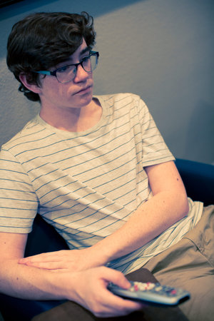 Teenager watching television in media room.の写真素材