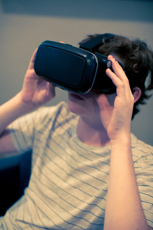 Teenage boy watching movie on VR goggles.