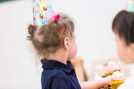 Cute girl celebrating 3rd birthday with her friends at school.の写真素材