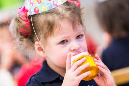 Cute girl celebrating 3rd birthday with her friends at school.の写真素材