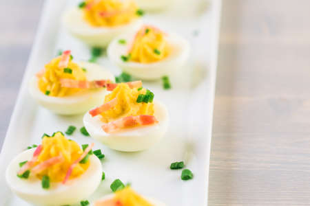 Deviled eggs garnished with green onions and bacon.の写真素材