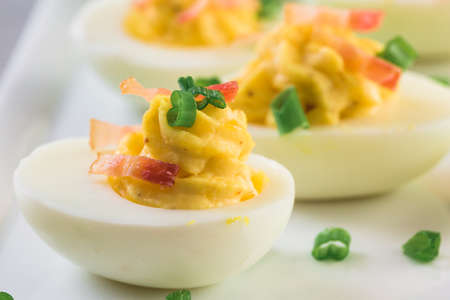 Deviled eggs garnished with green onions and bacon.の写真素材