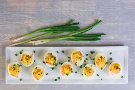 Deviled eggs garnished with green onions and bacon.の写真素材