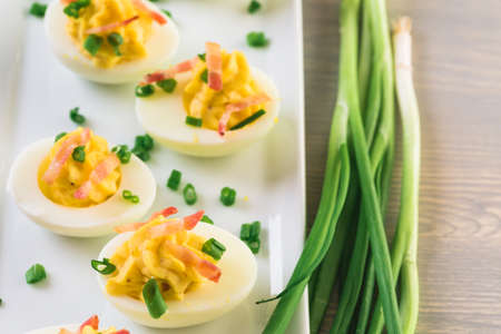 Deviled eggs garnished with green onions and bacon.の写真素材
