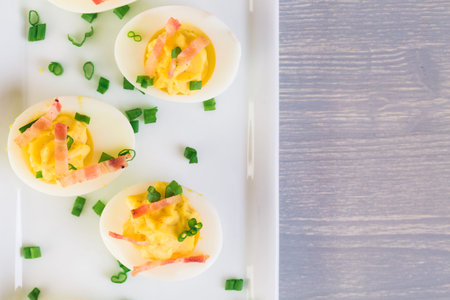 Deviled eggs garnished with green onions and bacon.の写真素材