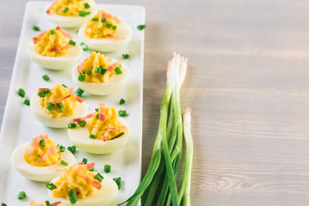 Deviled eggs garnished with green onions and bacon.の写真素材