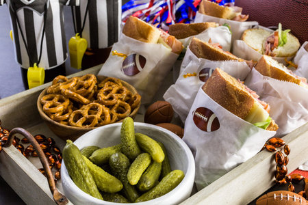Game day football party table with  sub sandwich and snacks.