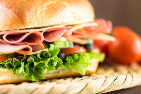 Sub sandwich with fresh vegetables, lunch meat and cheese on hoagie roll.