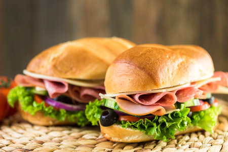 Sub sandwich with fresh vegetables, lunch meat and cheese on hoagie roll.