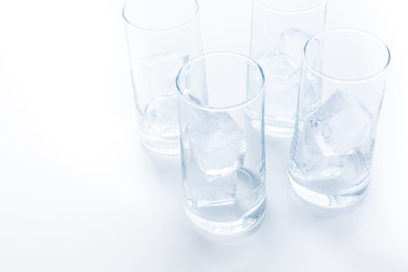 Empty glasses with large ice cubes on a white background.の写真素材