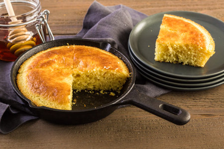 Slice of sweet cornbread with honey on the plate.