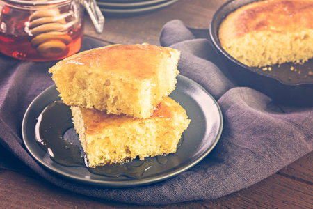 Slice of sweet cornbread with honey on the plate.