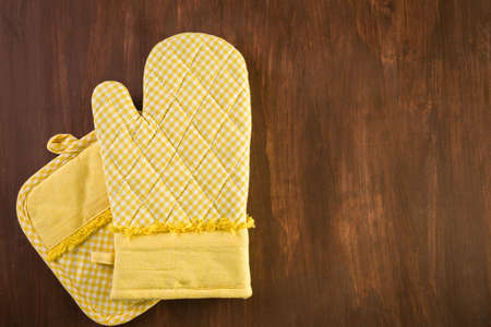 Yellow oven mitt on wood background.の写真素材