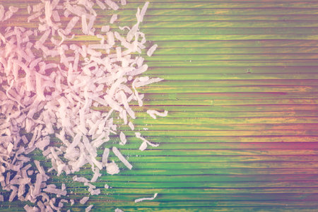 Dehydrated coconut flakes on a green background.