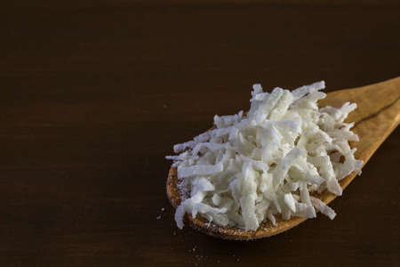 Dehydrated coconut flakes on a wood background.の写真素材