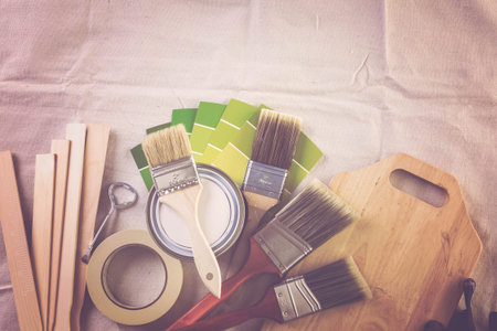 Paint in metal paint can and painters tools on a canvas drop cloth.