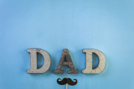 Metal letters DAD on a painted wood background.の写真素材
