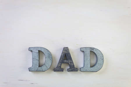 Metal letters DAD on a painted wood background.の写真素材
