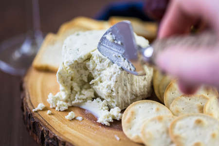 Soft flavored creamy cheese with garlic and fine herbs on a wood board with crackers.の写真素材