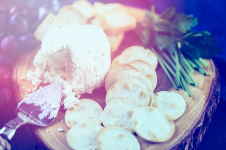 Soft flavored creamy cheese with garlic and fine herbs on a wood board with crackers.