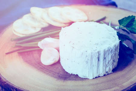 Soft flavored creamy cheese with garlic and fine herbs on a wood board with crackers.の写真素材