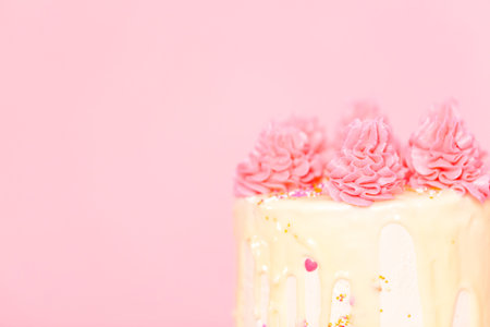 Pink and white buttercream cream cake with pink sprinkles and white chocolate ganache drip.