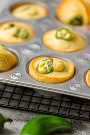 Freshly baked cornbread muffins with spicy jalapeno pepper in muffin pan.